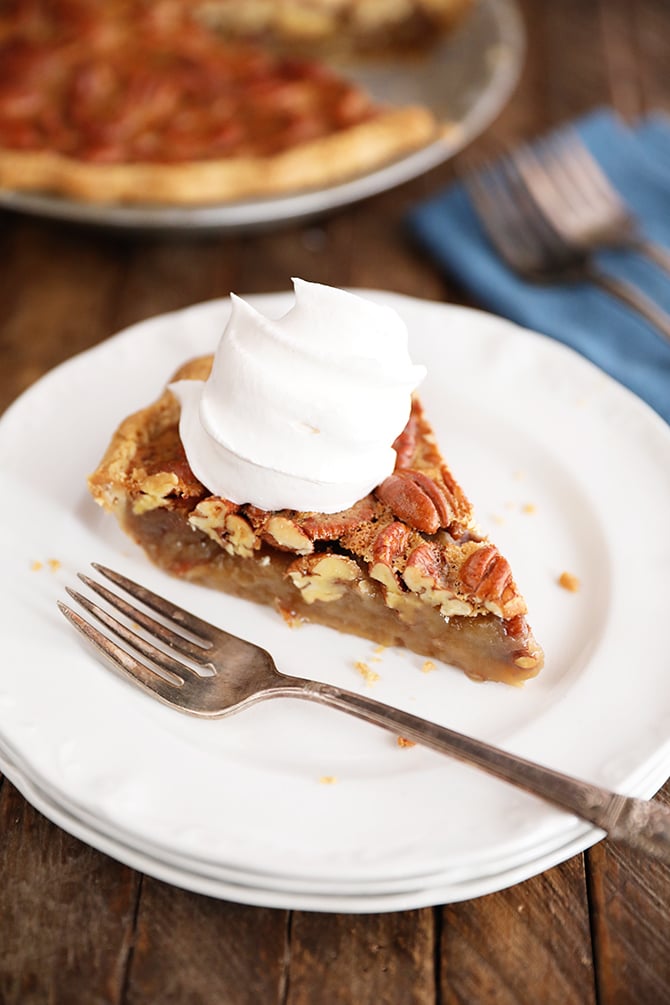 Slice of The Best Southern Pecan Pie with a slice missing with a dollop of whipped cream