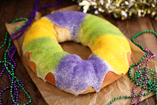 King Cake on brown paper with Mardi Gras beads