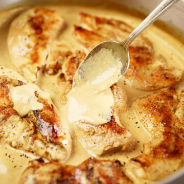 Cream Cheese Pan sauce being spooned over seared chicken breasts