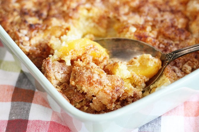 Peach Cobbler being scooped from baking dish