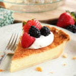 Slice of Buttermilk Pie with whipped topping and fruit on top