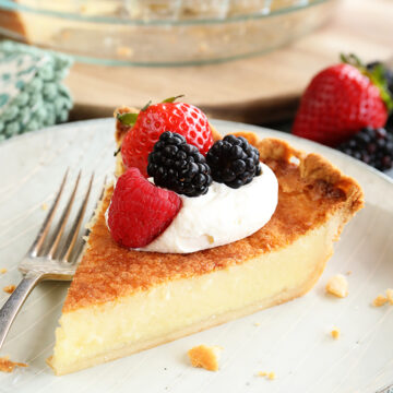 Slice of Buttermilk Pie with whipped topping and fruit on top