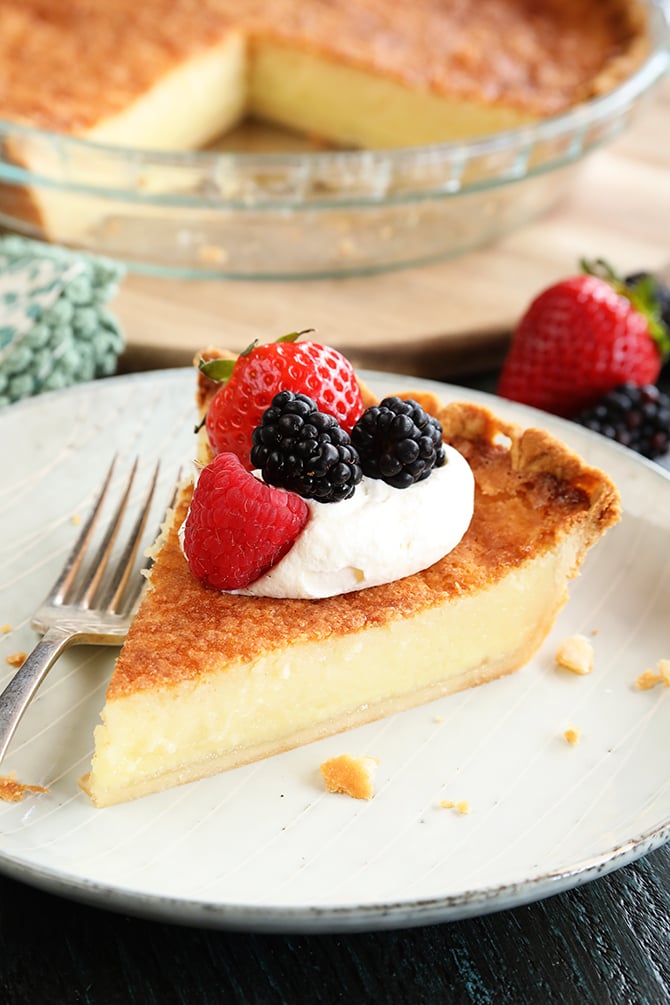 Slice of Buttermilk Pie with whipped topping and fruit on top