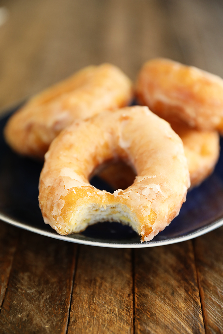Glaze doughnut with bite missing.