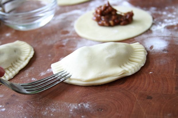 Crimping the edges of the pies with a fork