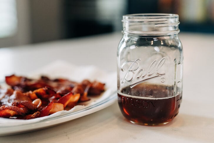 plate of bacon with jar of bacon grease.