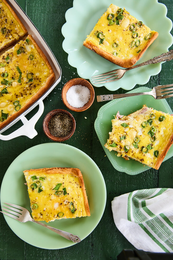 Overhead view of slices of ham and swiss brunch bake on plates.
