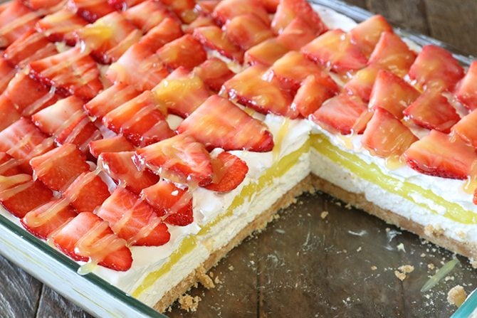 This recipe for Strawberry lemon Lush is sure to be your new favorite layered dessert! A Nilla Wafer crust topped with a layer of sweetened cream cheese, lemon pie filling, whipped topping, and it's all topped off with fresh strawberries drizzled in lemon curd!