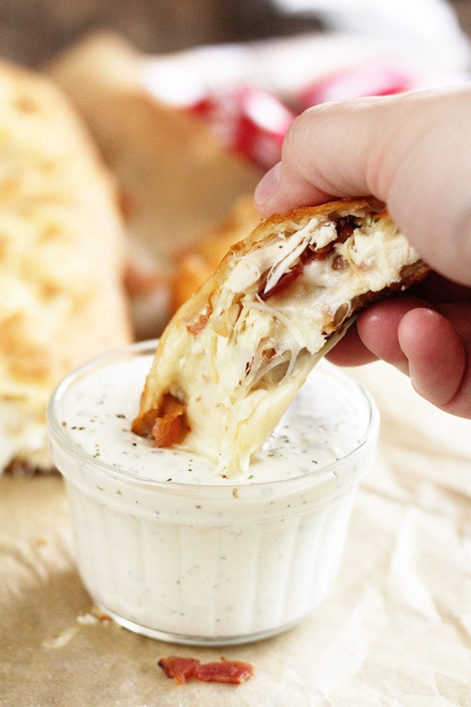 Chicken Bacon Ranch Stromboli being dipped in sauce