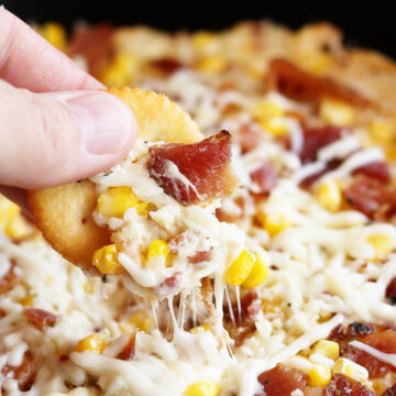 Cheese Bacon Corn dip being dipped with cracker
