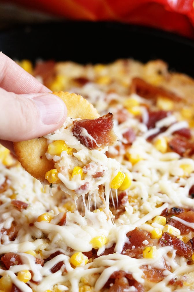 Cheese Bacon Corn dip being dipped with cracker