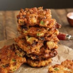 Okra and Green Tomato Fritters stacked on brown parchment paper.