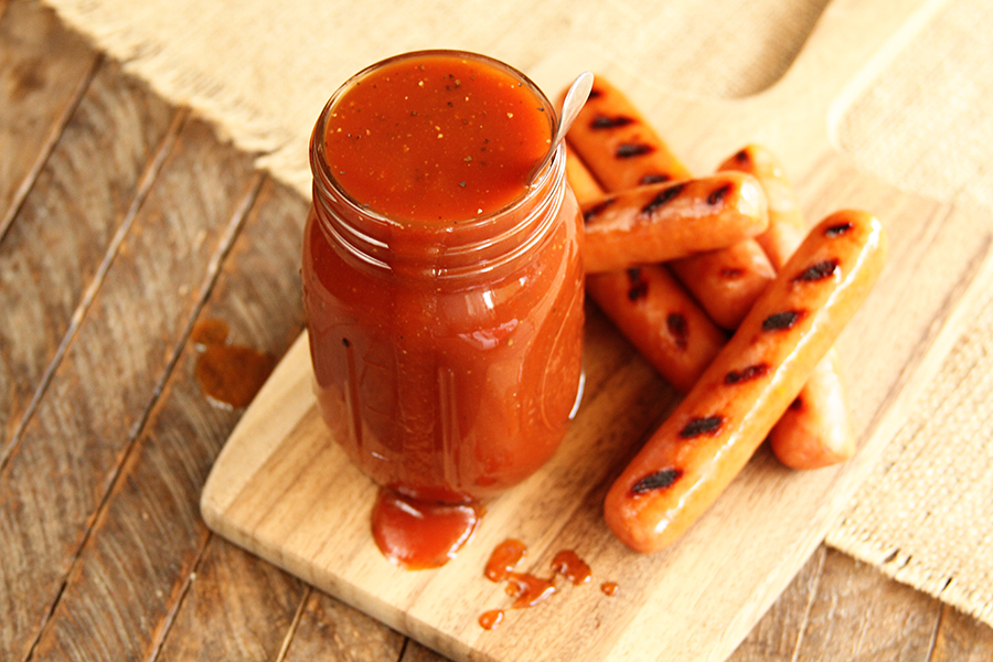 Jar of Coca Cola BBQ Sauce on wooden serving bowl with hot dogs