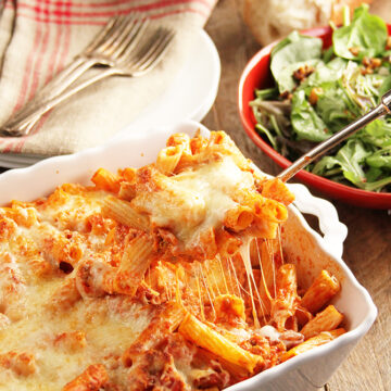 Cheesy Baked Ziti in casserole dish being served with spoon