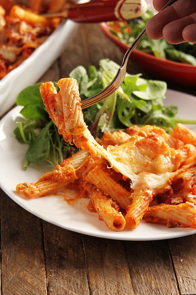 Cheesy Baked Ziti in white plate with salad