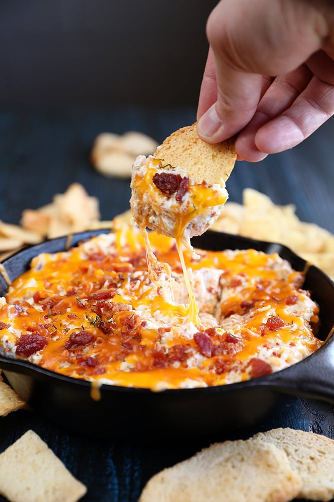 Cheesy Chicken Bacon Ranch Dip scooping out of pan with a chip