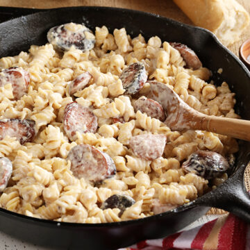 Weeknight Sausage Alfredo in cast iron skillet and break in background