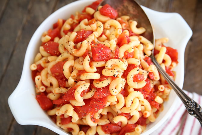 Macaroni and tomatoes with serving spoon