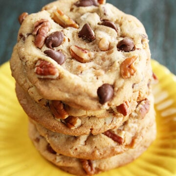 Chocolate Chip toffee Pecan Cookies stacked on yellow plate