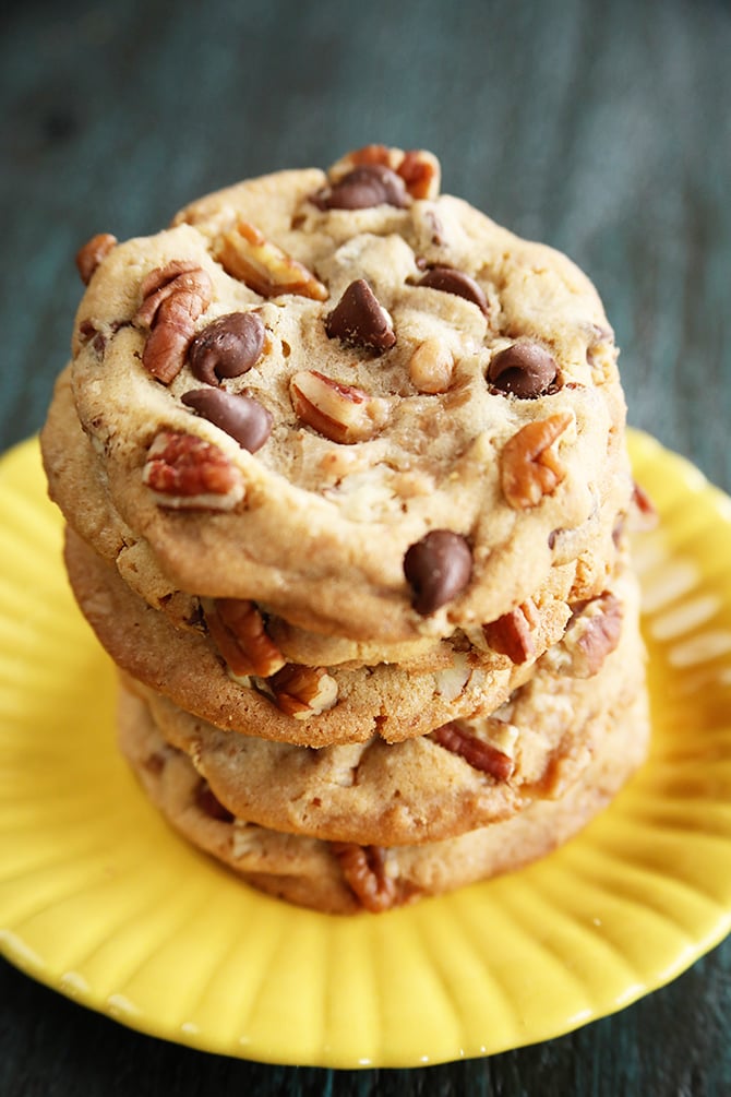 Chocolate Chip toffee Pecan Cookies stacked on yellow plate