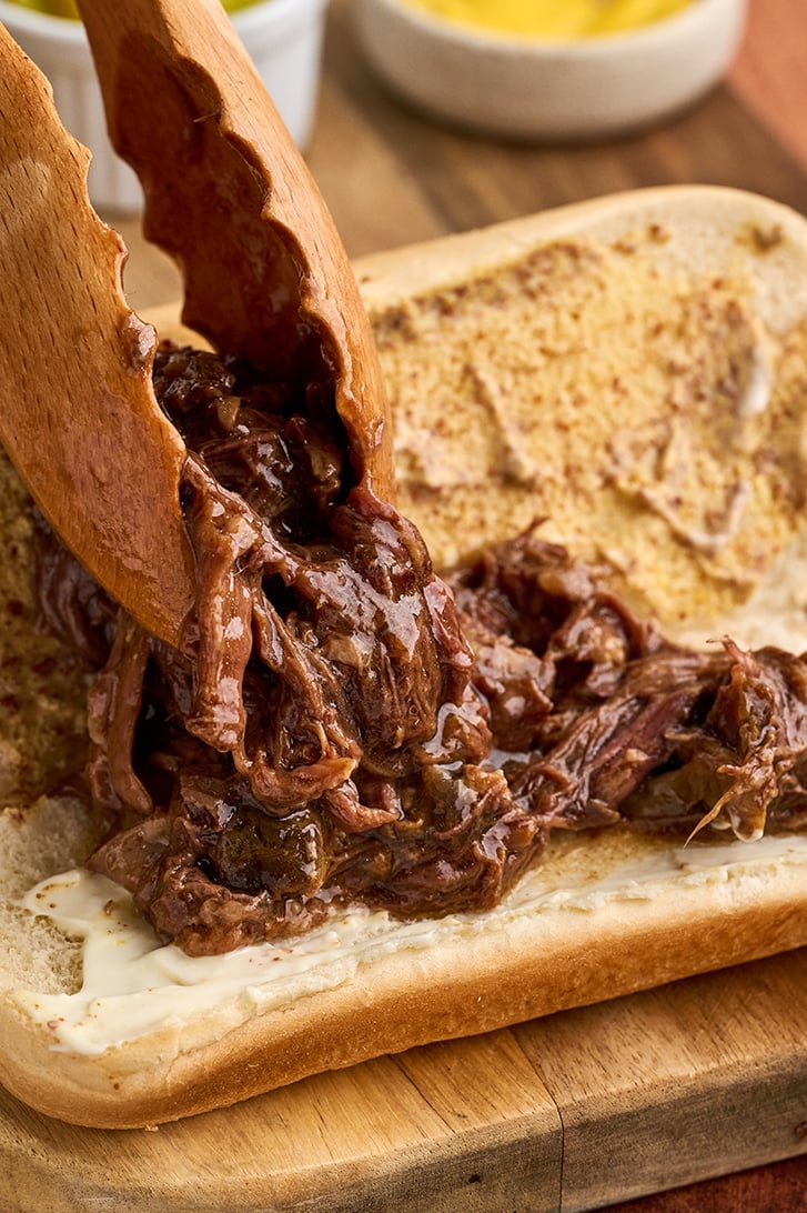 Putting shredded roast beef on a bun.