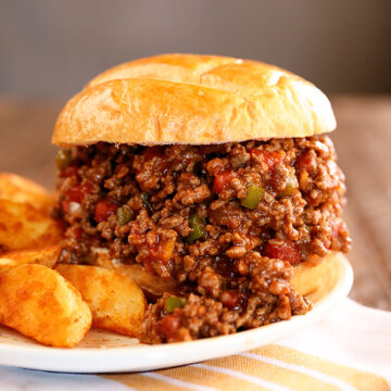 Creole Sloppy Joes on a white plate with potato wedges