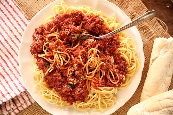 Slow Cooker Spaghetti Sauce over cooked spaghetti on a white plate