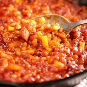 Spoonful of Bacon Pineapple Baked Beans in a cast iron skillet