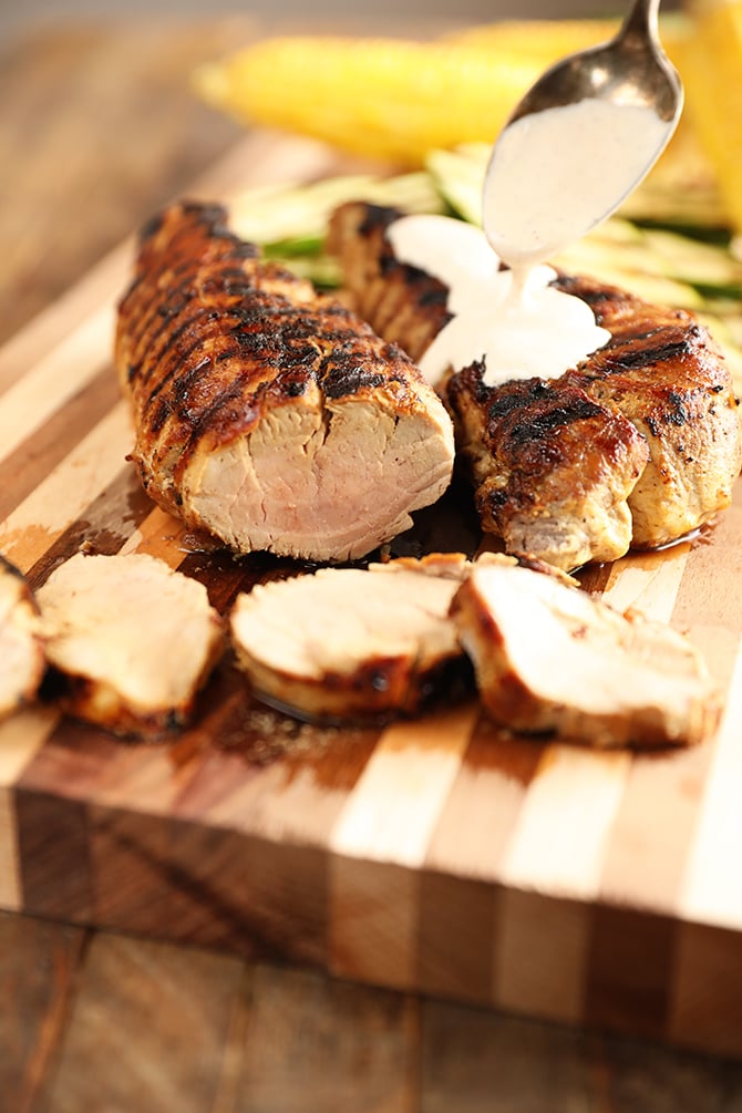Grilled Pork tenderloin with white bbq sauce being poured over it