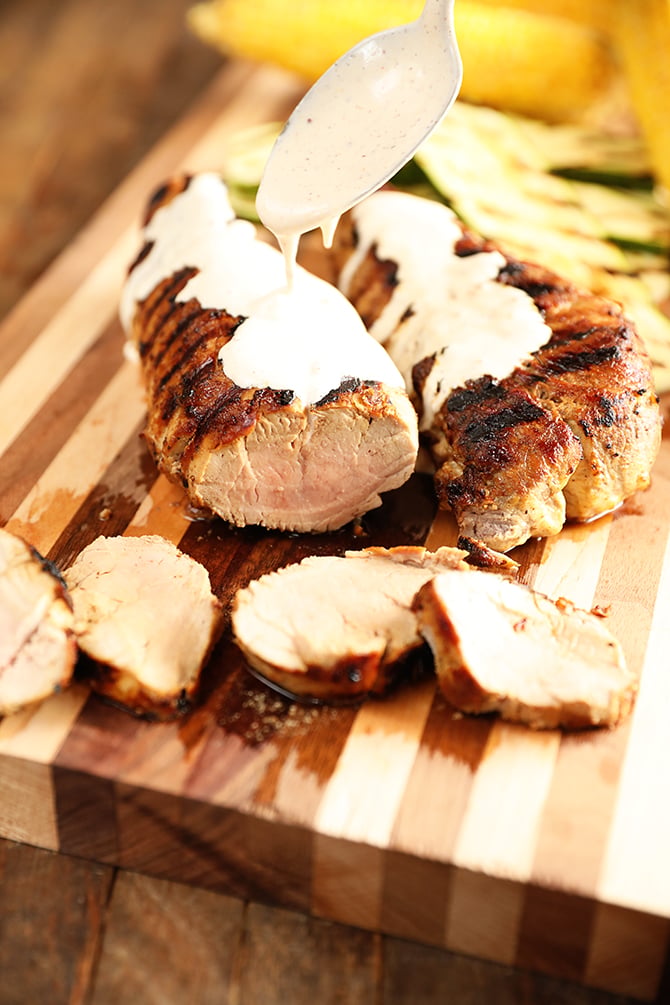 Grilled Pork tenderloin with white bbq sauce being poured over it