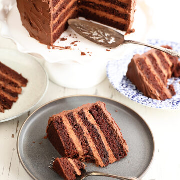 Slices of Triple Chocolate Mousse Cake on plates with large cake in the background