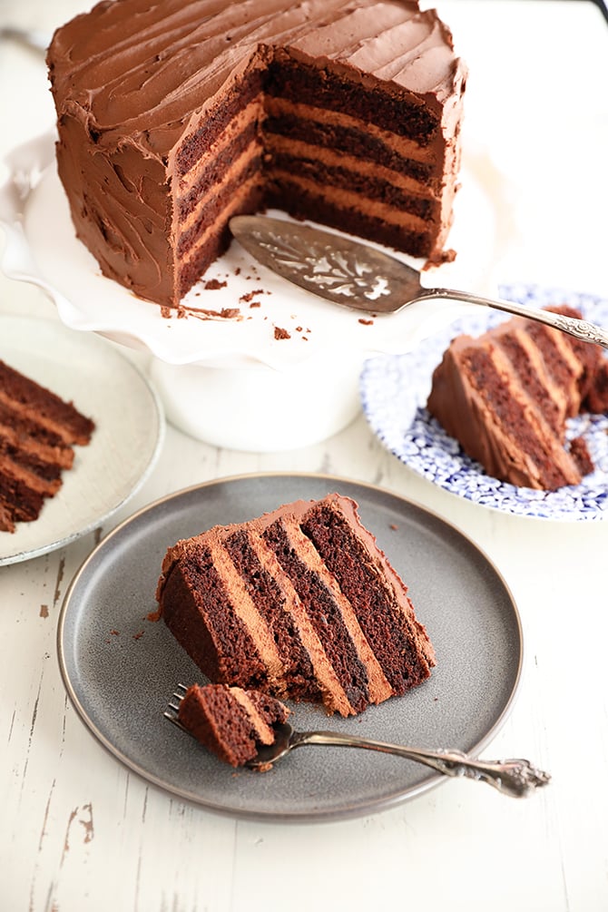 Slices of Triple Chocolate Mousse Cake on plates with large cake in the background