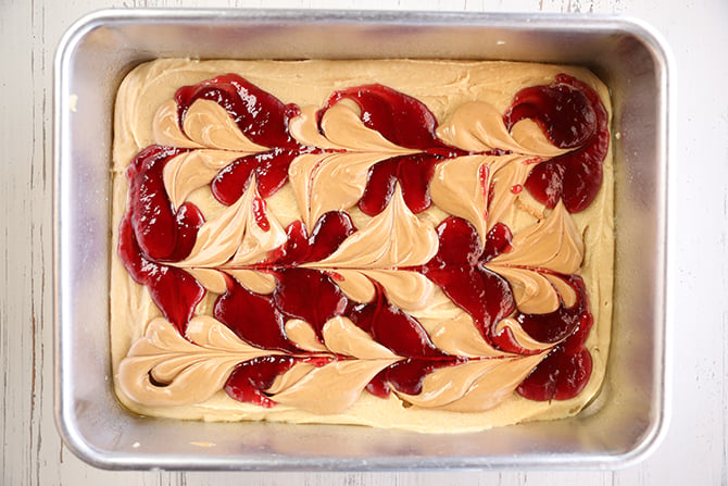 Blondie batter with dollops of peanut butter and jelly swirled together