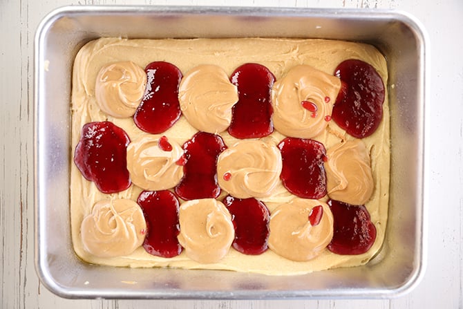 Blondie batter with dollops of peanut butter and jelly on top