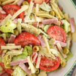 Salad with tomatoes, ham, olives, artichokes, and cheese.