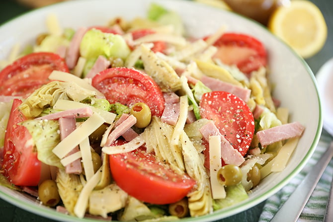 Salad with tomatoes, ham, olives, artichokes, and cheese.