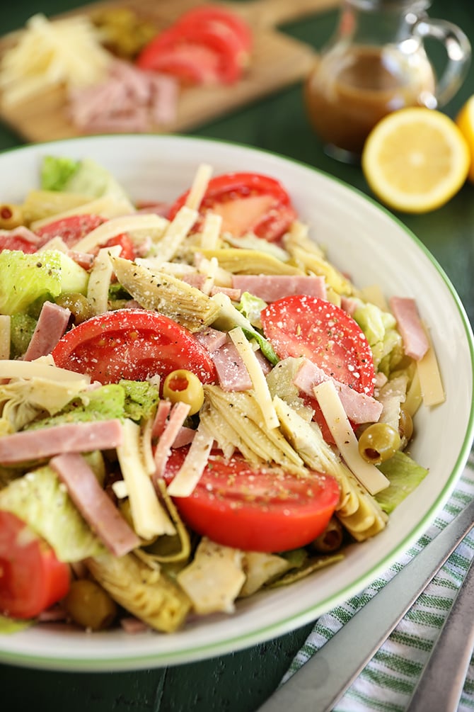 Salad with tomatoes, ham, olives, artichokes, and cheese.