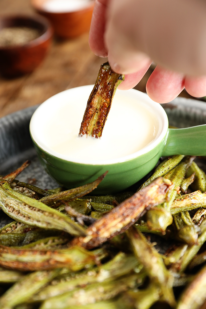 Crispy Roasted Okra being dipped into the creamy lemon dressing