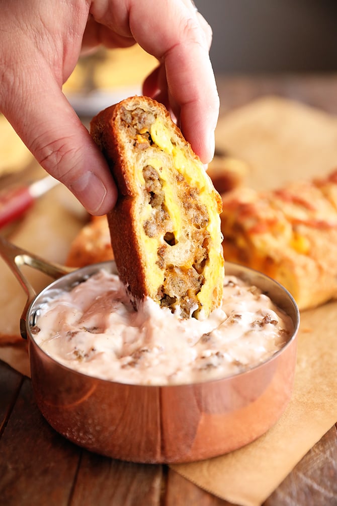 Slice of Breakfast Stromboli being dipped into sausage gravy
