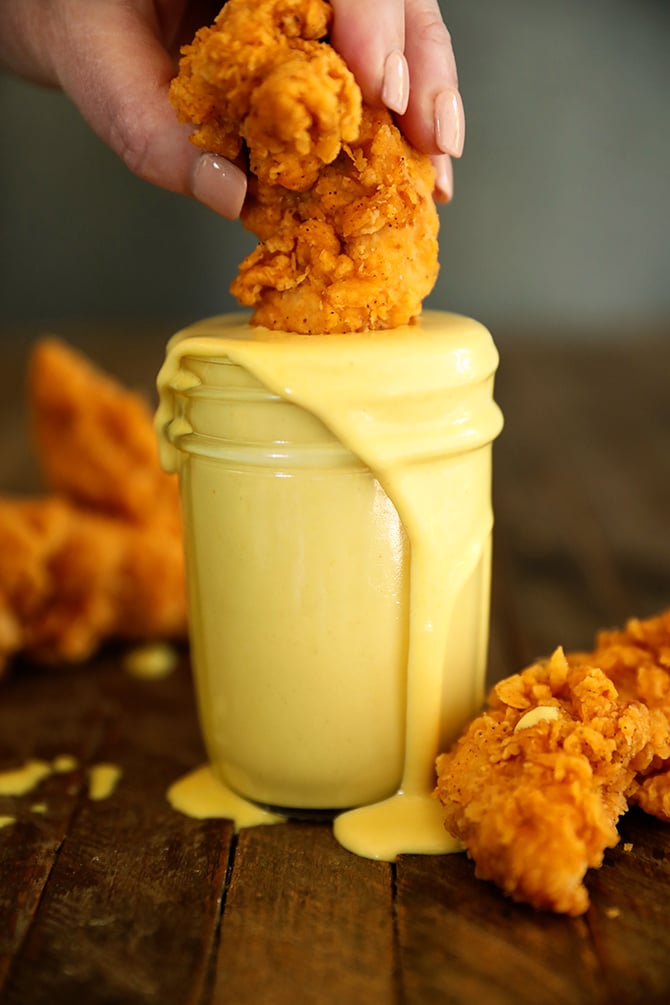 Chicken finger being dipped into Honey Mustard Dressing