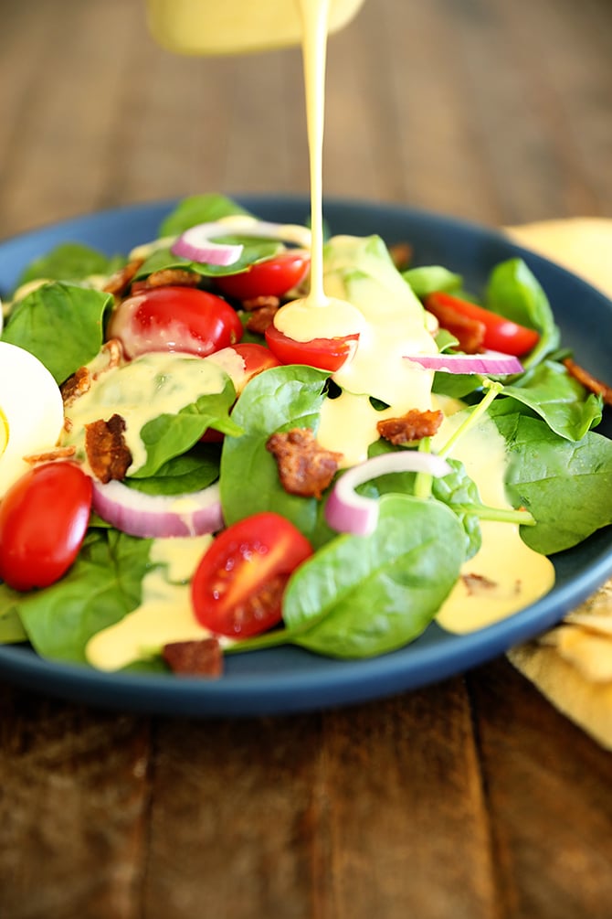 Honey Mustard Dressing being drizzled over a spinach salad