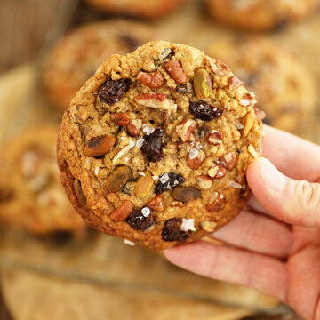 Single Chocolate, Cherry, Pistachio, Pecan Cookie in hand