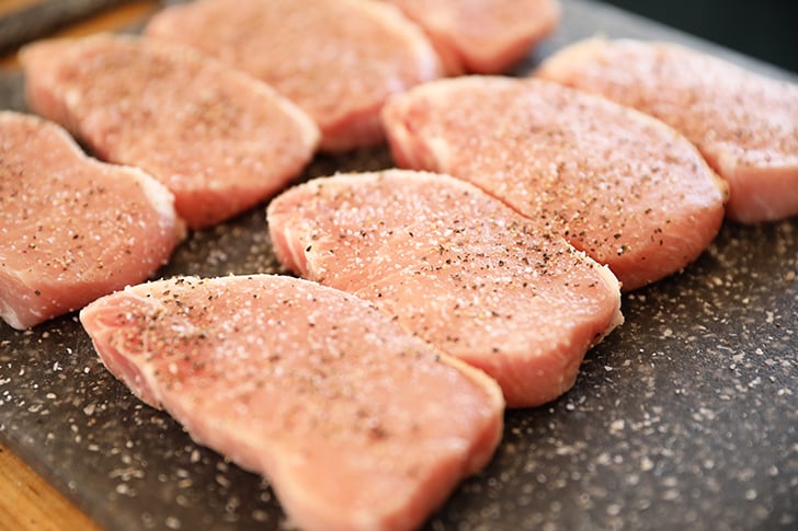 raw pork chops on cutting board