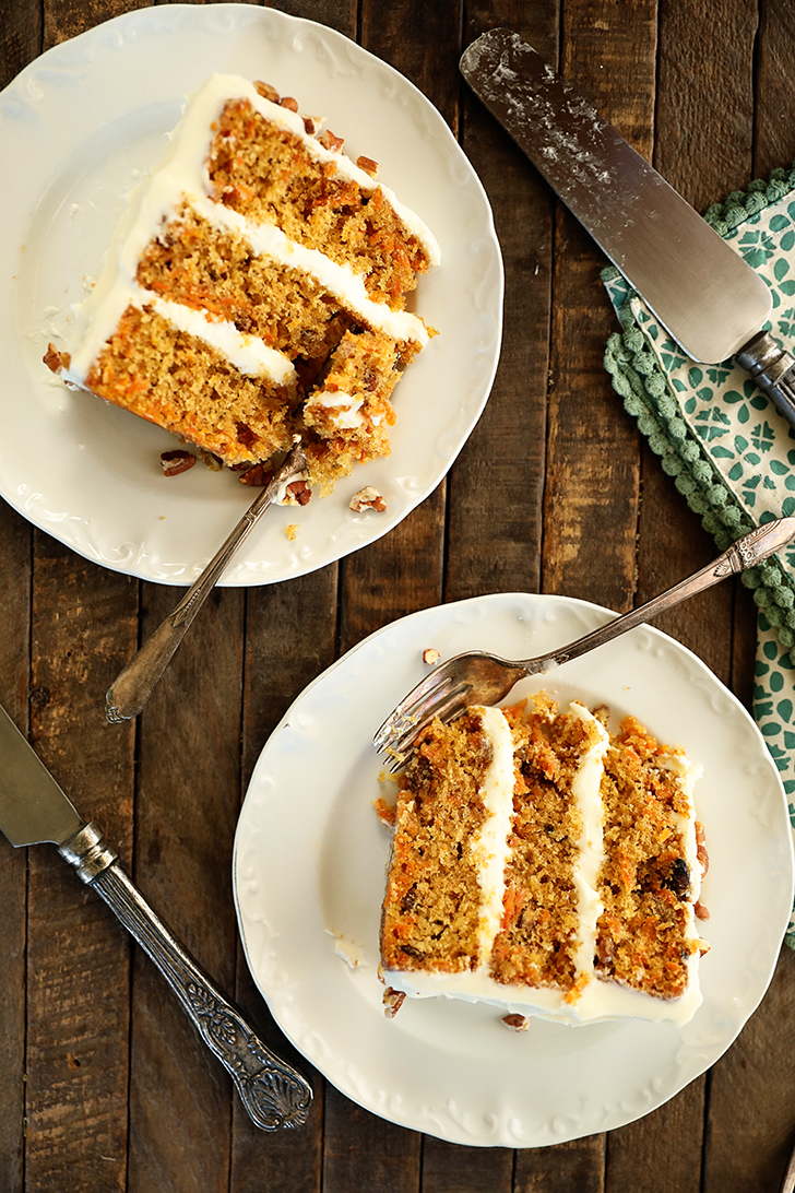 Overhead view of slices of carrot cake on white plates.