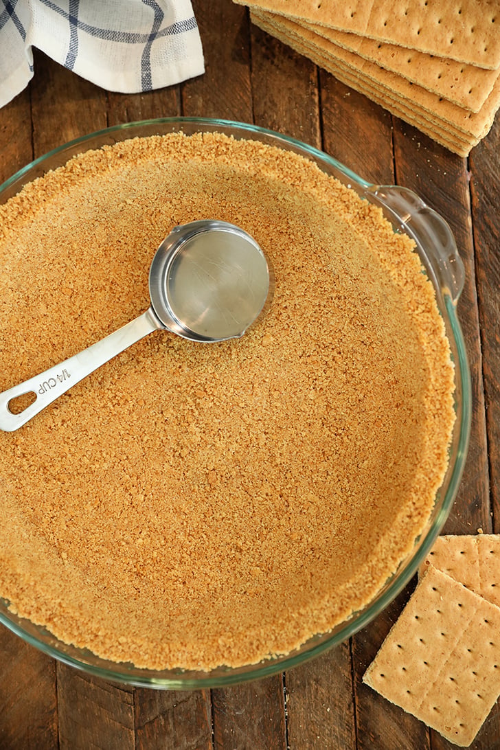 Overhead view of graham cracker crust with measuring cup.