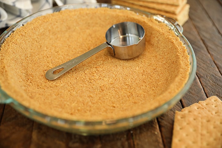 Graham cracker crust with measuring cup.