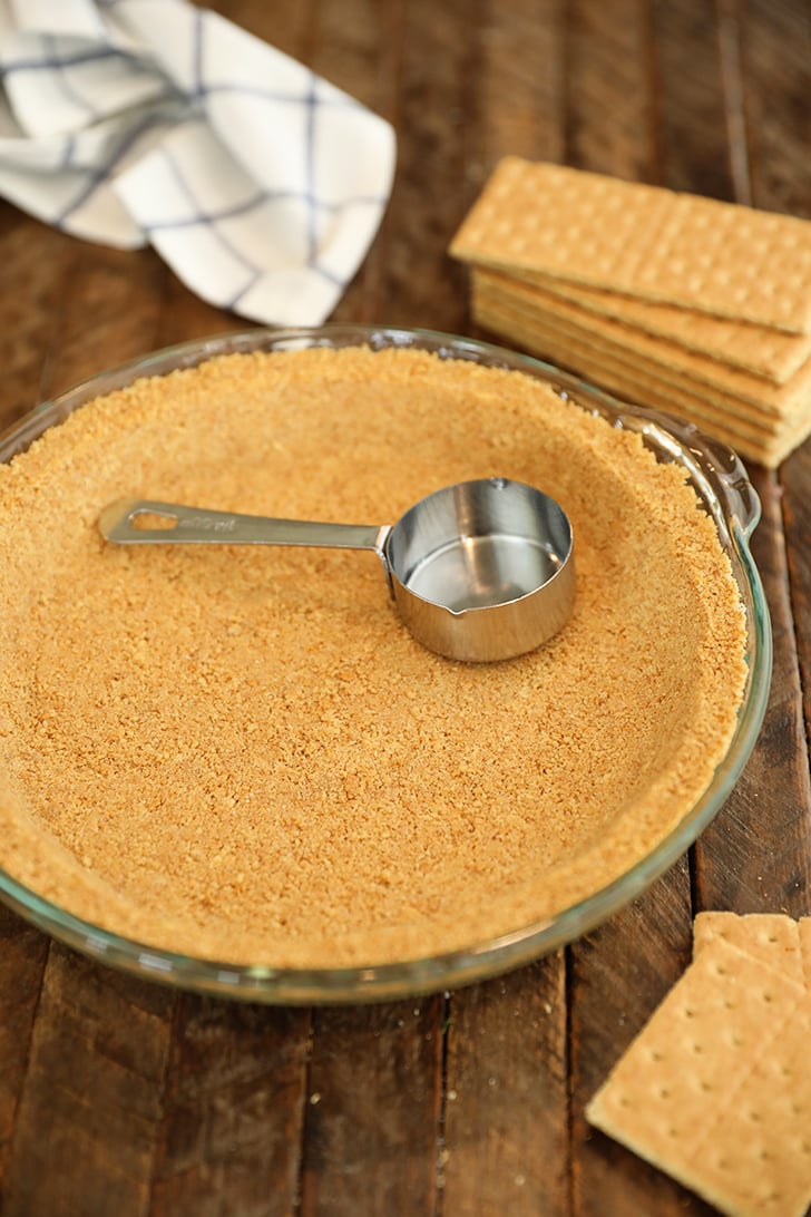 Graham cracker crust with measuring cup.