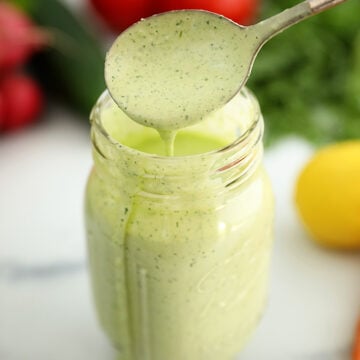 Pouring Green Goddess Salad Dressing into a jar.