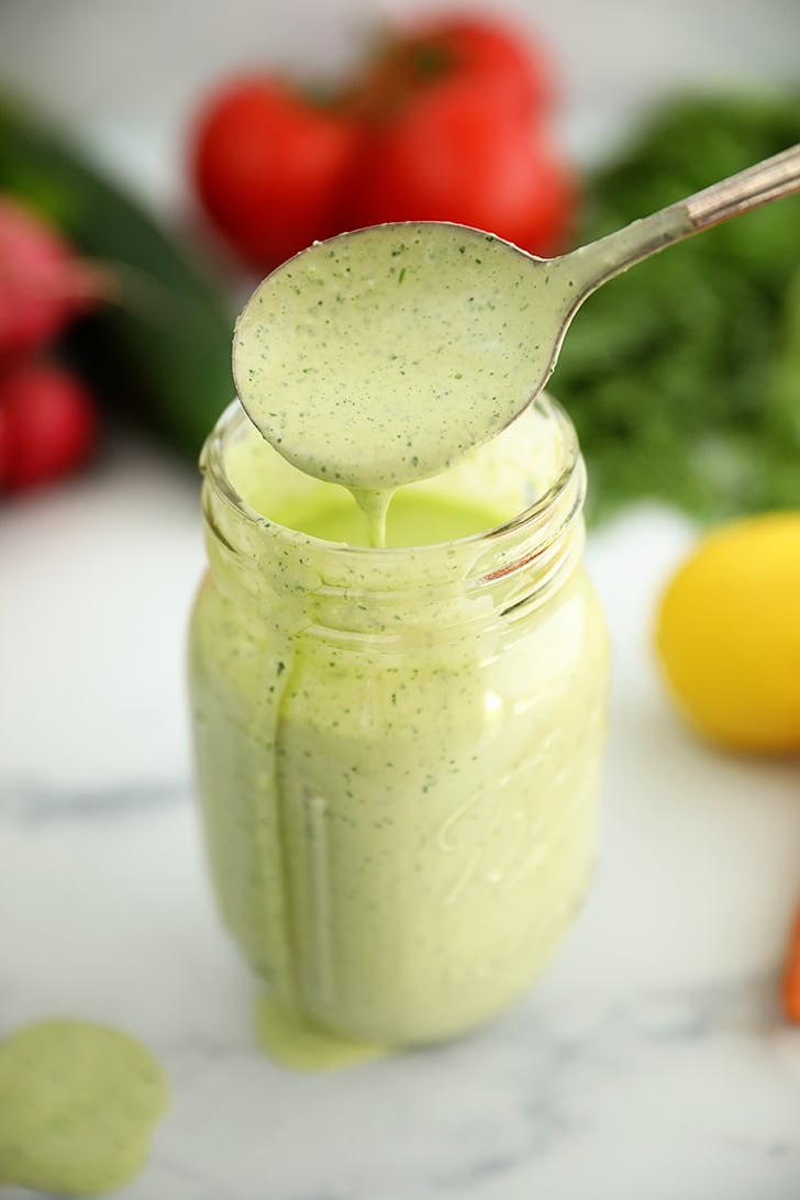 Pouring Green Goddess Salad Dressing into a jar.