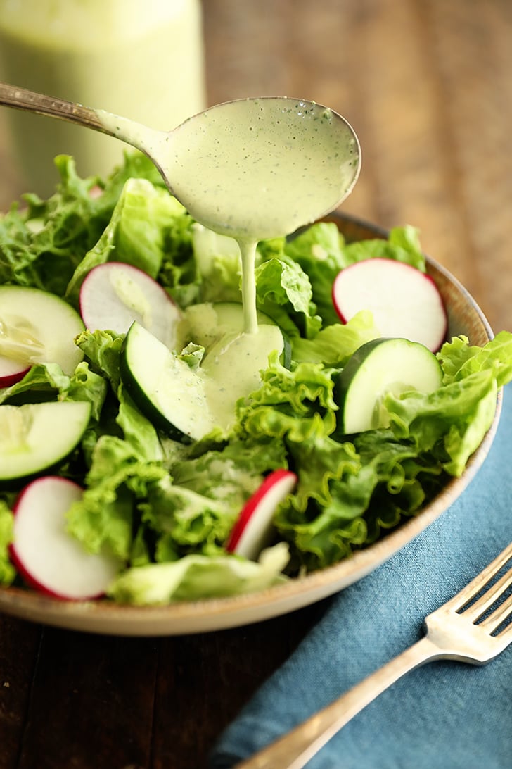Pouring Green Goddess Salad Dressing over a salad.